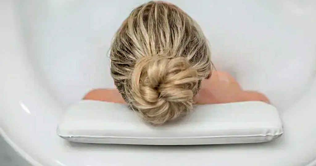blonde woman laying head on white bath pillow
