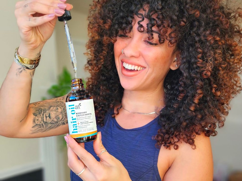 woman holding bottle of artnaturals hair oil