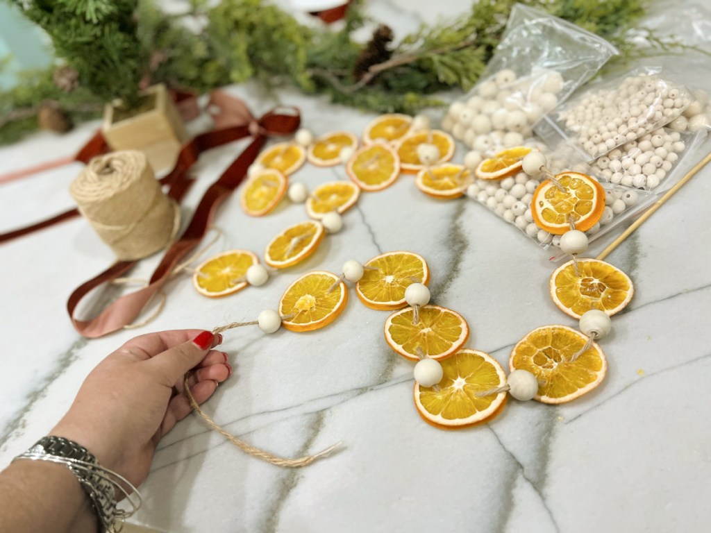 compiling a dried orange garland with twine and wood beads