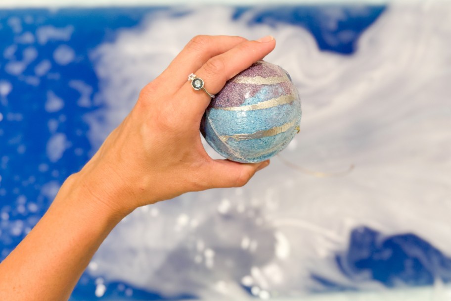 hand holding bath bomb wearing ring