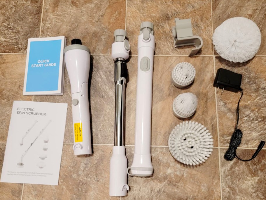 electric spin brush accessories and parts laying out on tile with instruction manual