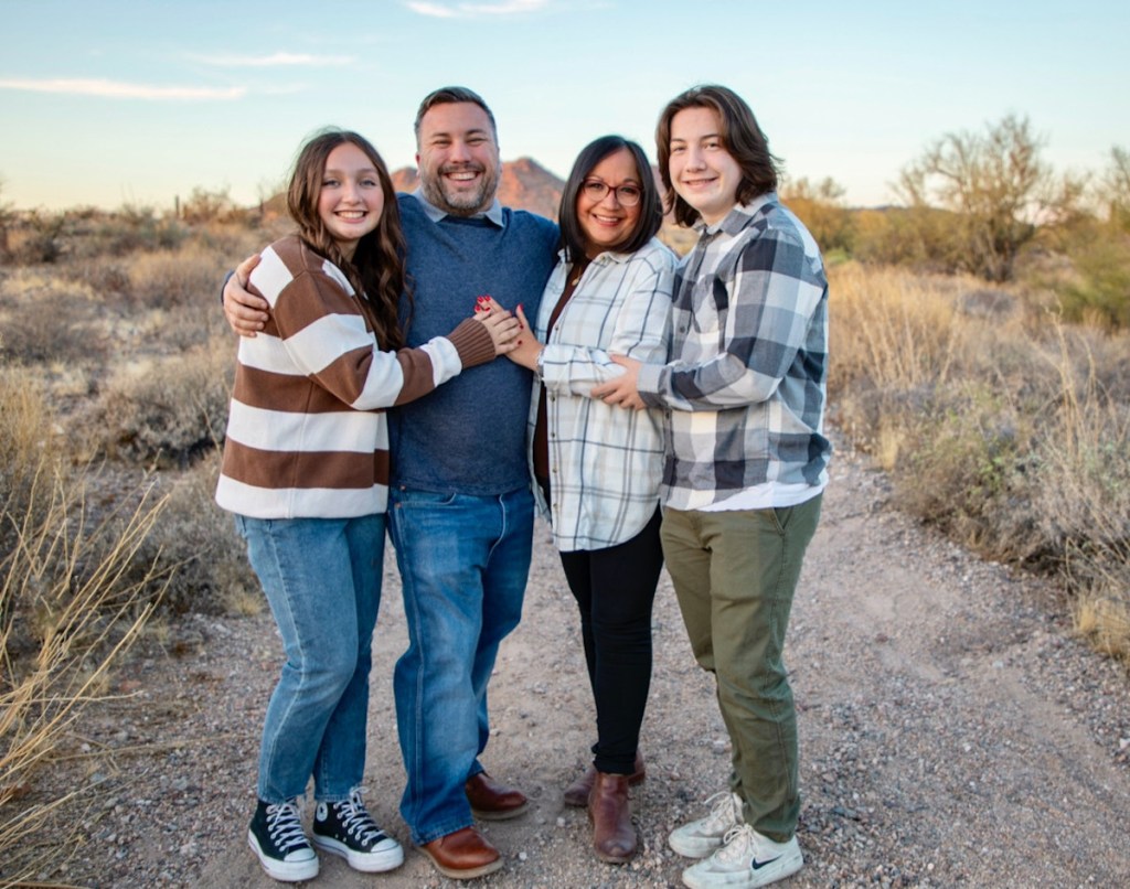 family standing in pathway outside in field 