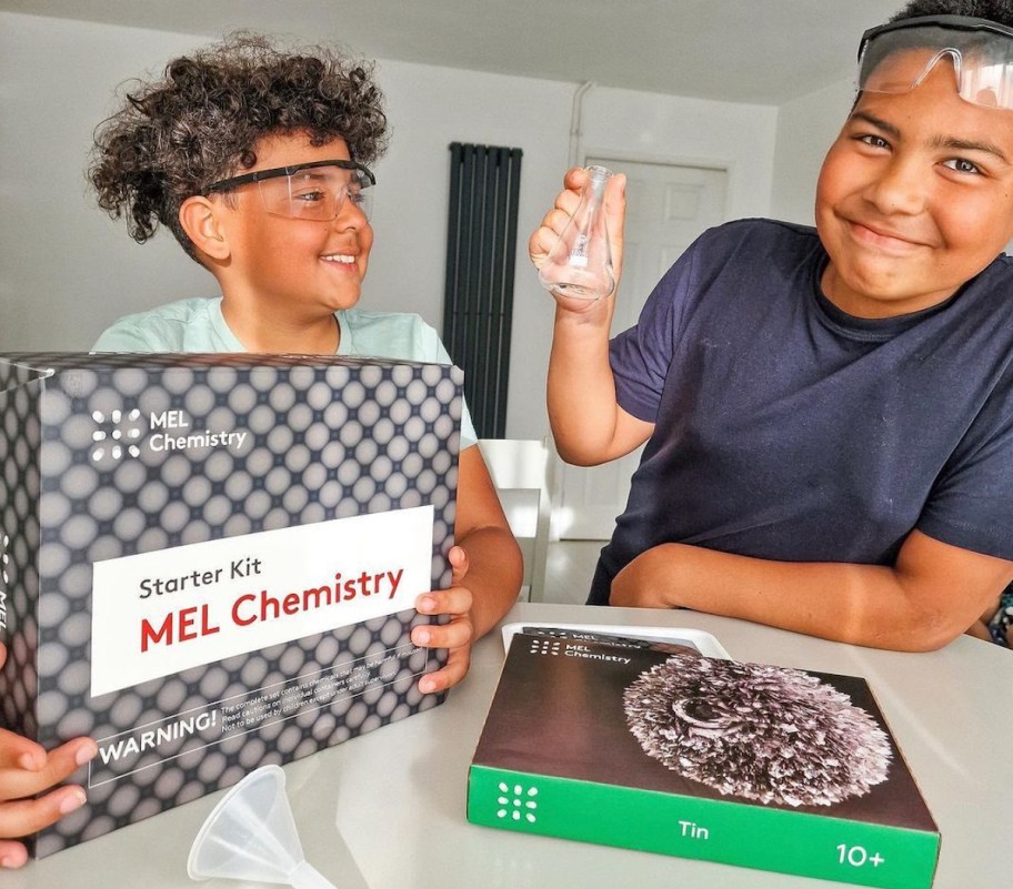 two boys sitting at counter with mel chemistry science kits