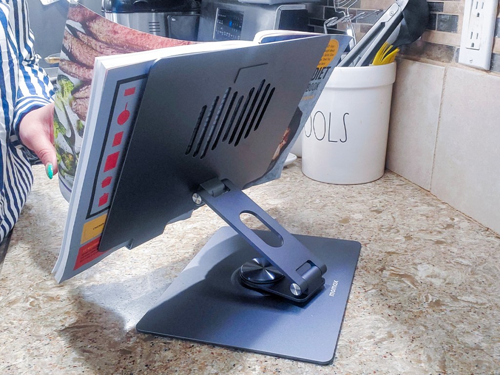 person reading book sitting on laptop stand