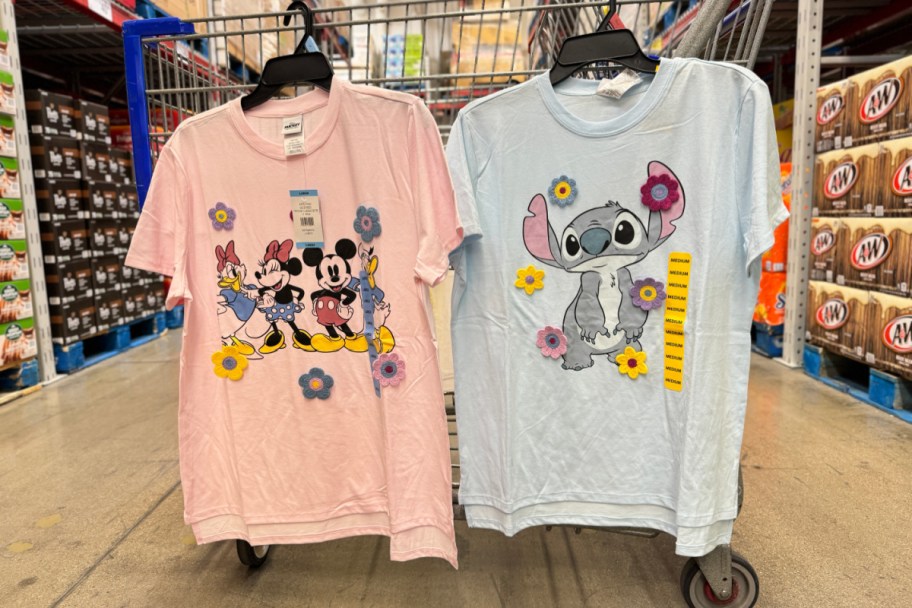 two disney tees hanging on shopping cart