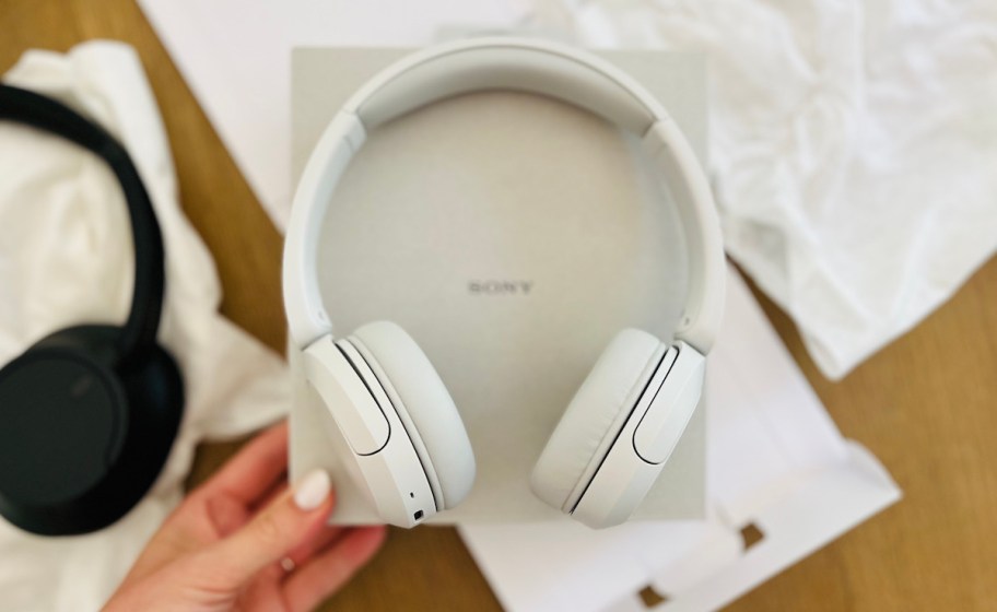 hand holding a sony box with white headphones on top