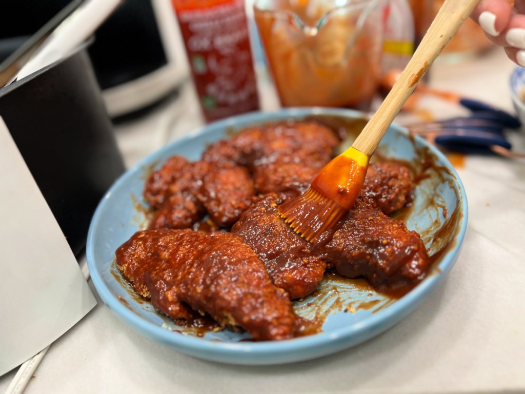 spreading sriracha sauce on chicken