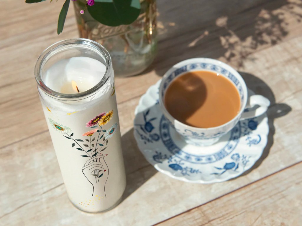 cathedral white candle with hand holding flowers on it 