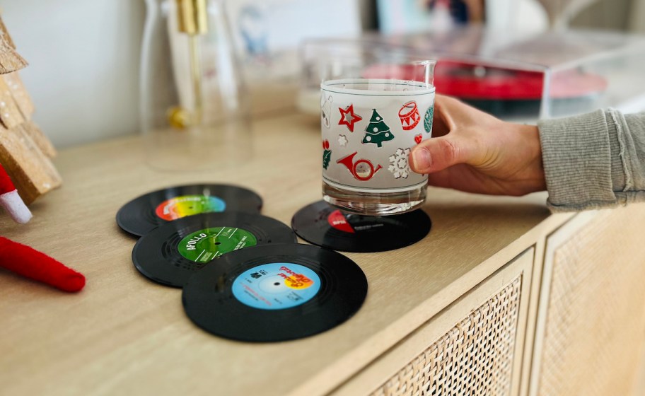 hand holding holiday glass with vinyl record coasters on table