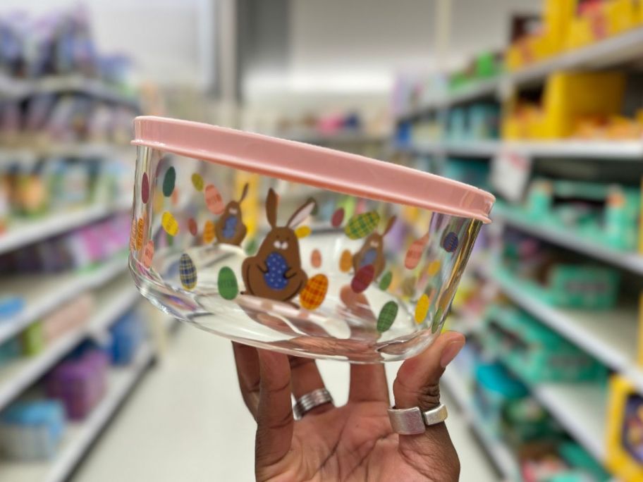 hand holding a glass food container with Easter bunny and eggs design on it and a pink lid