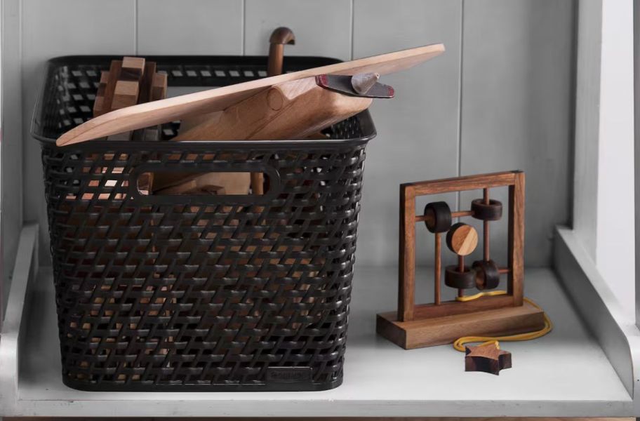 a black plastic woven storage basket on a shelf