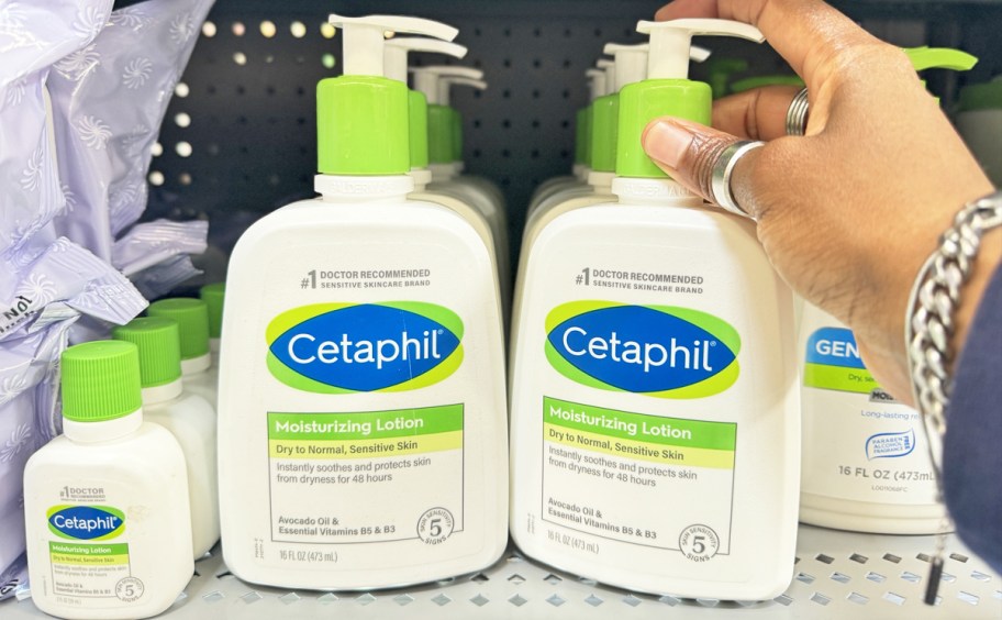 hand touching white and green Cetaphil Moisturizing Lotion 16oz Bottles on store shelf