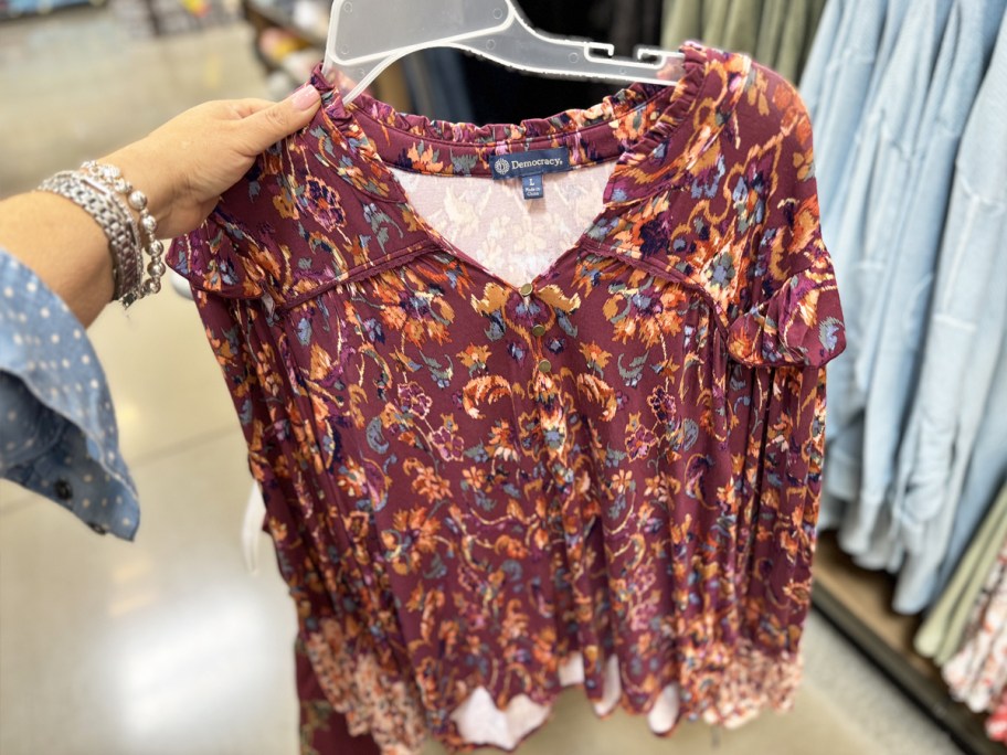 woman holding up a maroon floral printed dress on hanger