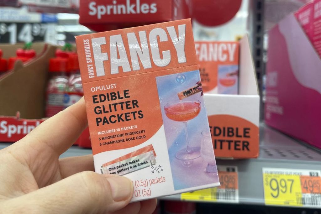 a womans hand holding a box of Fancy sprinkles decorating glitter in a walmart store