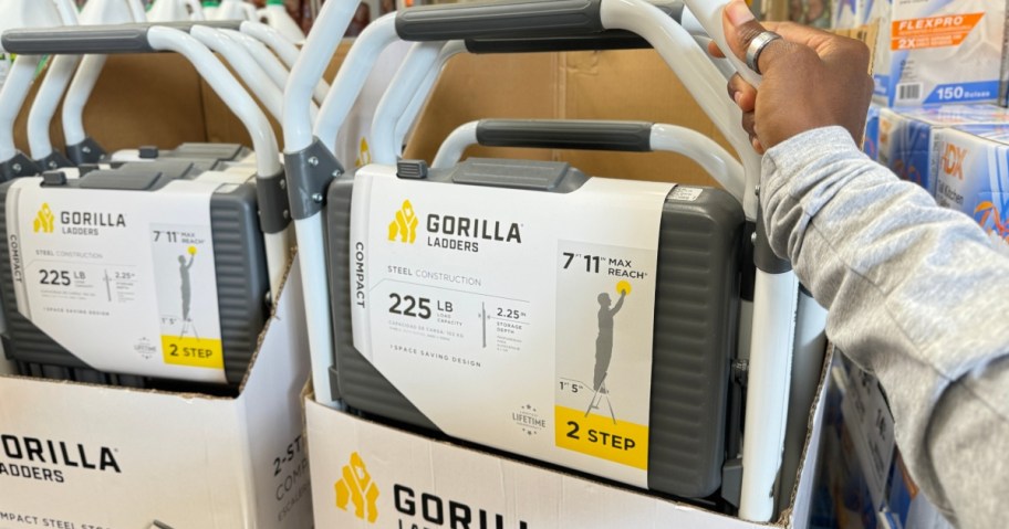 hand reaching for a Gorilla Ladders Step Stool in display box at Home Depot