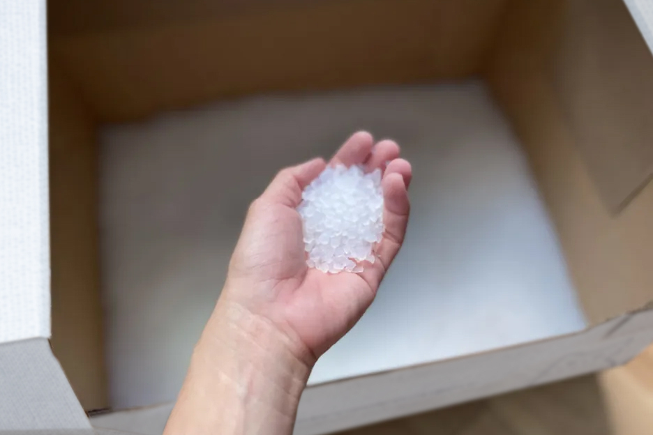 hand holding silica cat litter over kitty poo club box