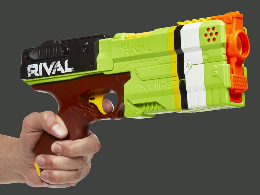 hand holding a green, brown, and orange nerf blaster