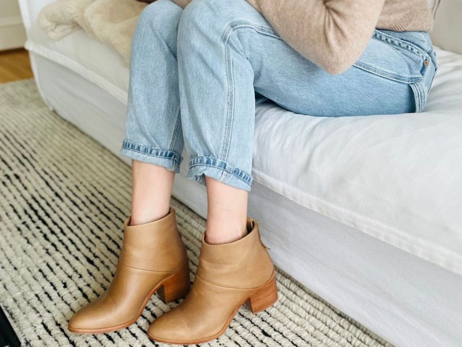 Woman sitting wearing a pair of Nisolo Dari boots