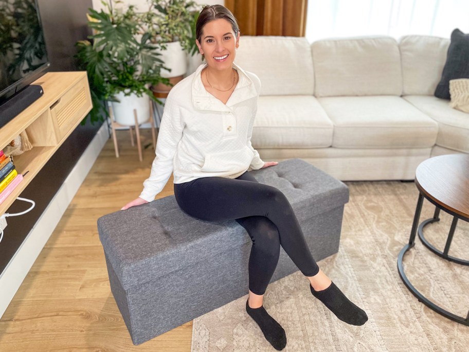 woman sitting on a grey storage ottoman