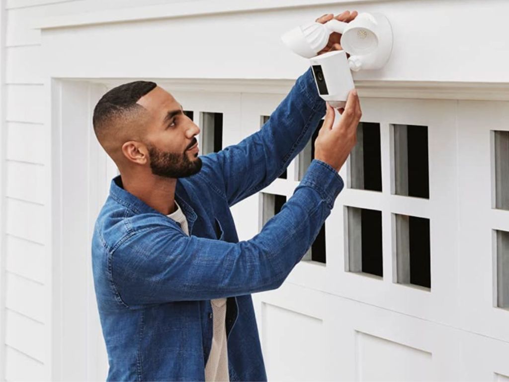 man installing a ring floodlight on his garage