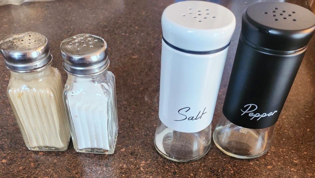set of standard glass salt & pepper shakers next to new large black & white ones
