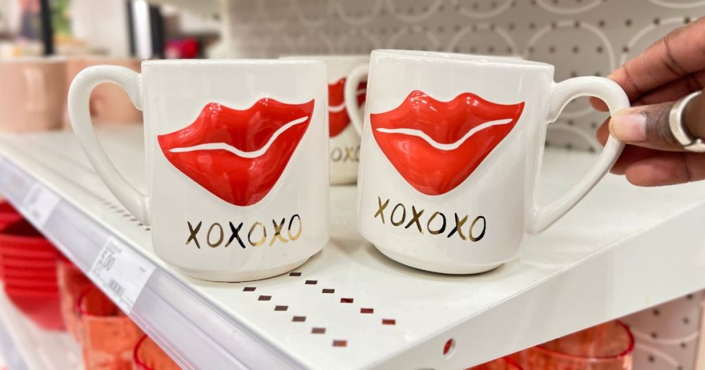 a womans hand reaching for a Threshold Valentine's Day Figural Embossed Lip Mug 15ozon a store shelf