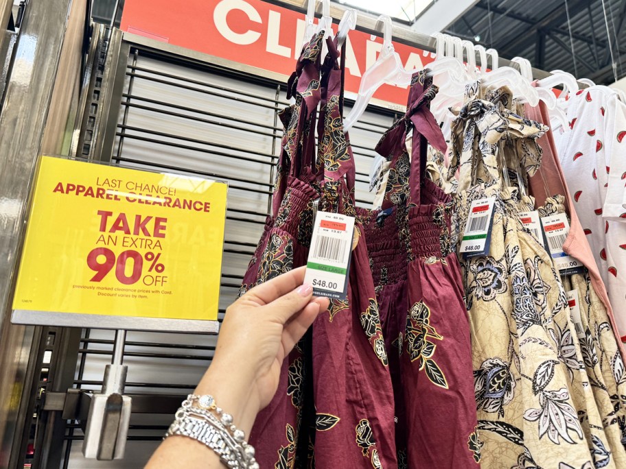 hand holding price tag from a floral print tank top