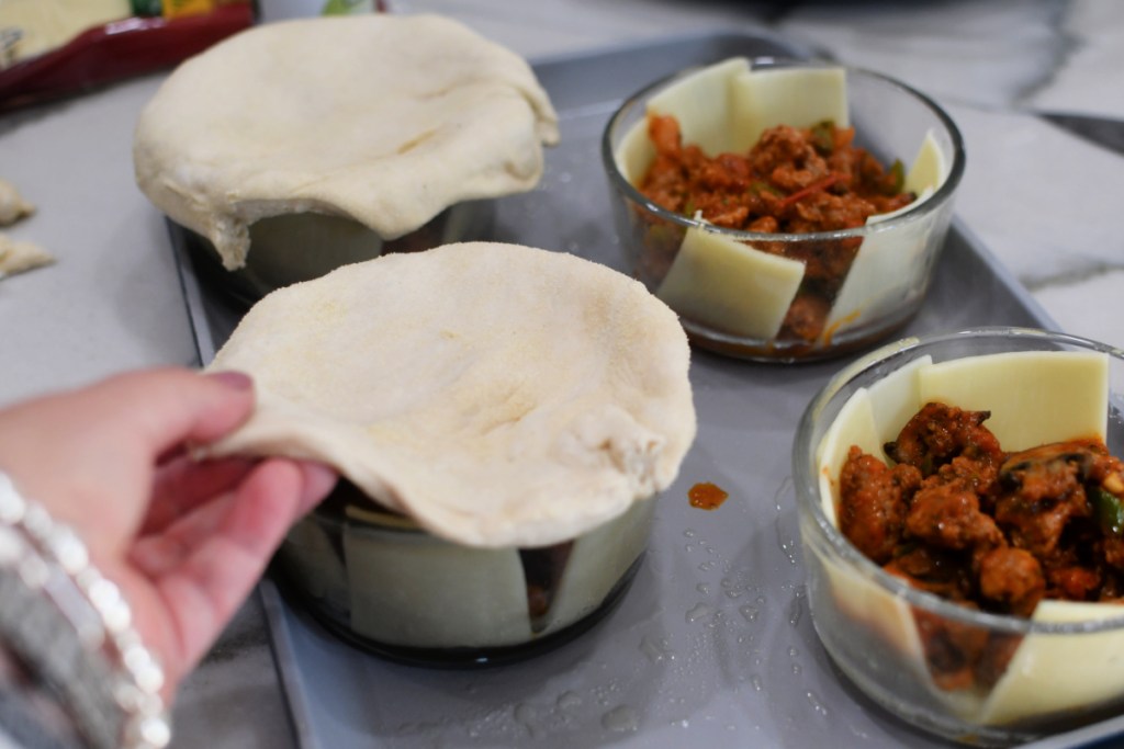 adding pizza dough to the top of bowls