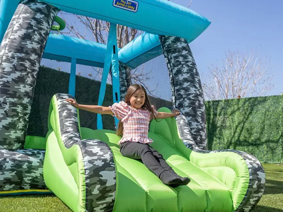 girl going down green bounce houses slide