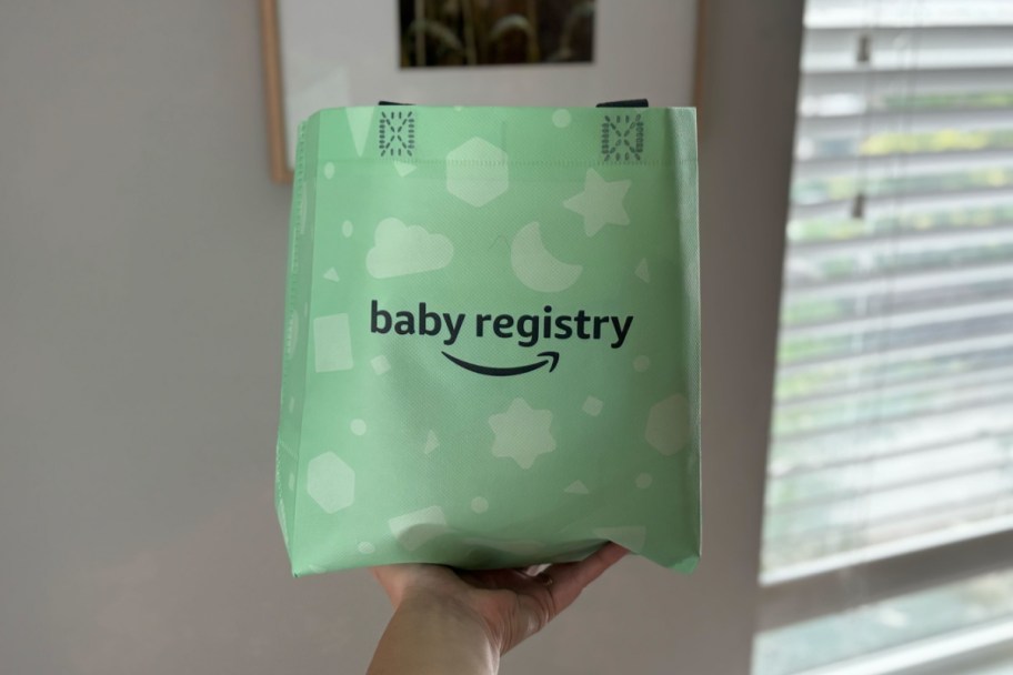 hand holding green baby registry bag