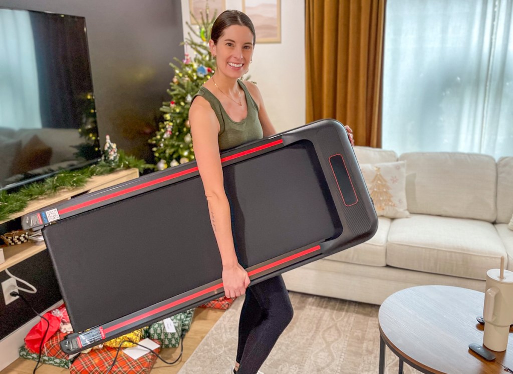 Woman holding walking pad and living room with Christmas tree and gifts