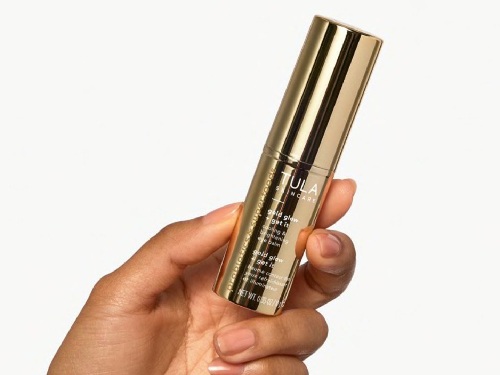 hand holding TULA eye balm in gold