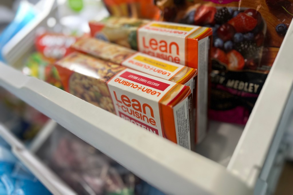 boxes of lean cuisine meals next to bagged frozen fruit in a freezer drawer