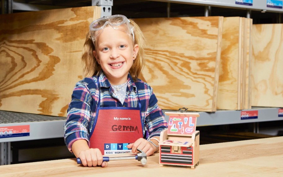 girl sitting at workbench with lowes apron on and tool bench craft on table