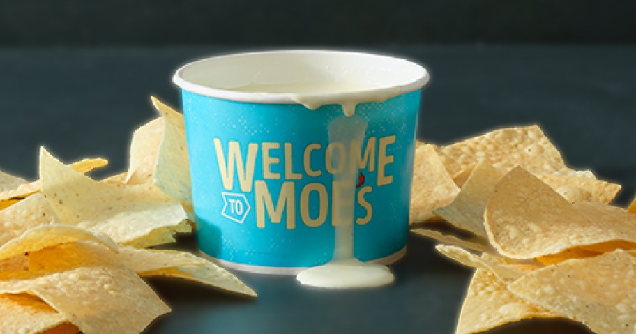 moes cup of queso with chips on table