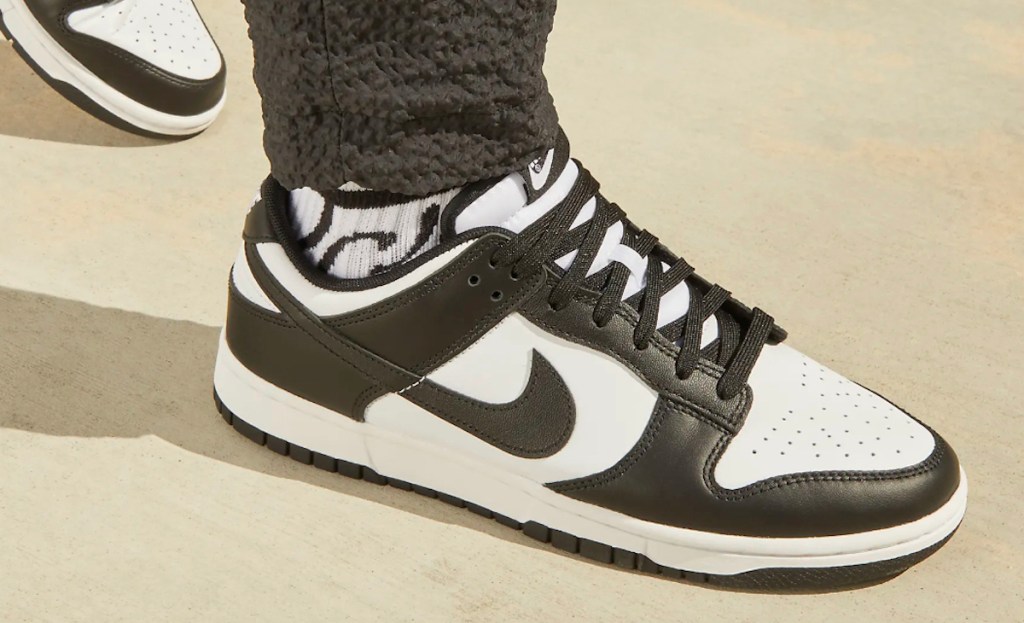 Close-up of person wearing white and black Nike dunks panda sneakers