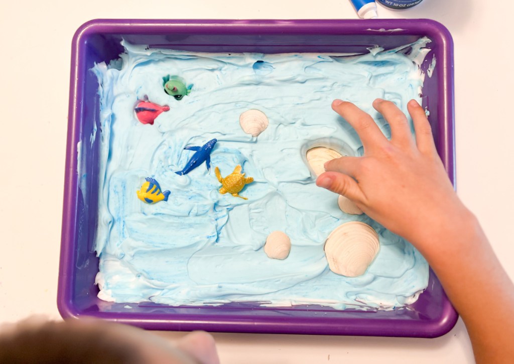 kid playing with shaving cream sensory bin