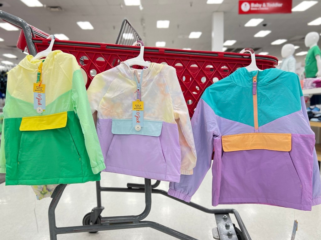 three kids raincoats hanging on target shopping cart