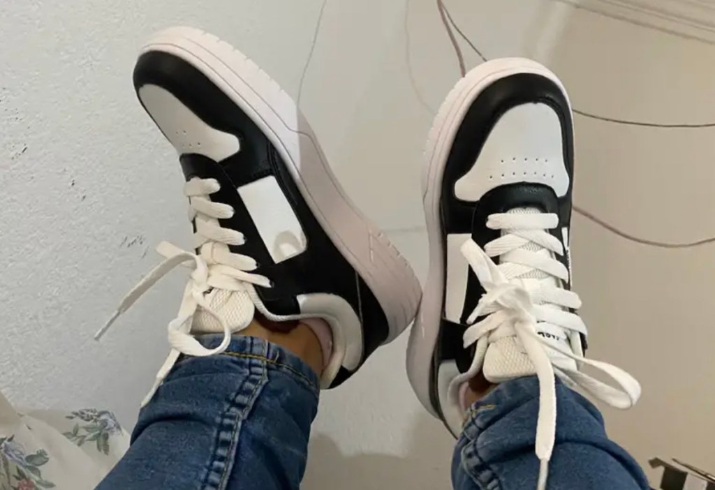 Close-up of person wearing black and white sneakers with jeans