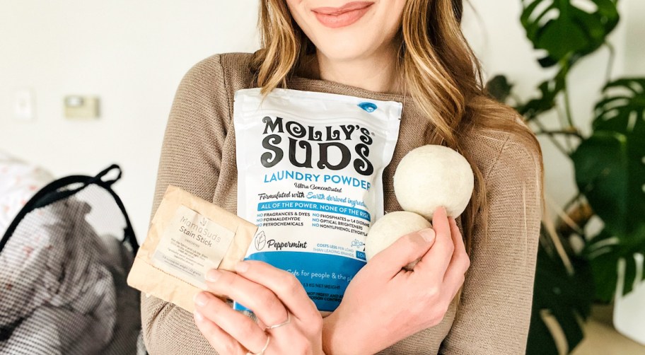 close up of woman holding clean laundry products in arms