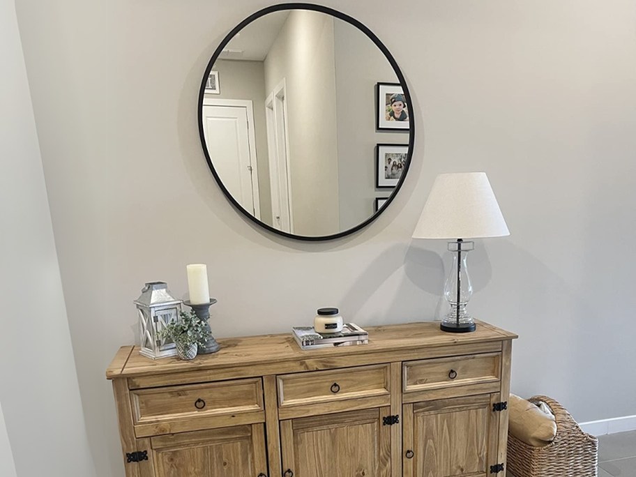 a large round wall mirror over a large dresser with decor on it