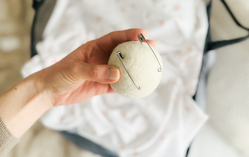 hand holding a wool ball with metal paper clips 