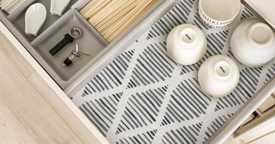 open kitchen drawer with grey pattern shelf liner and cutlery