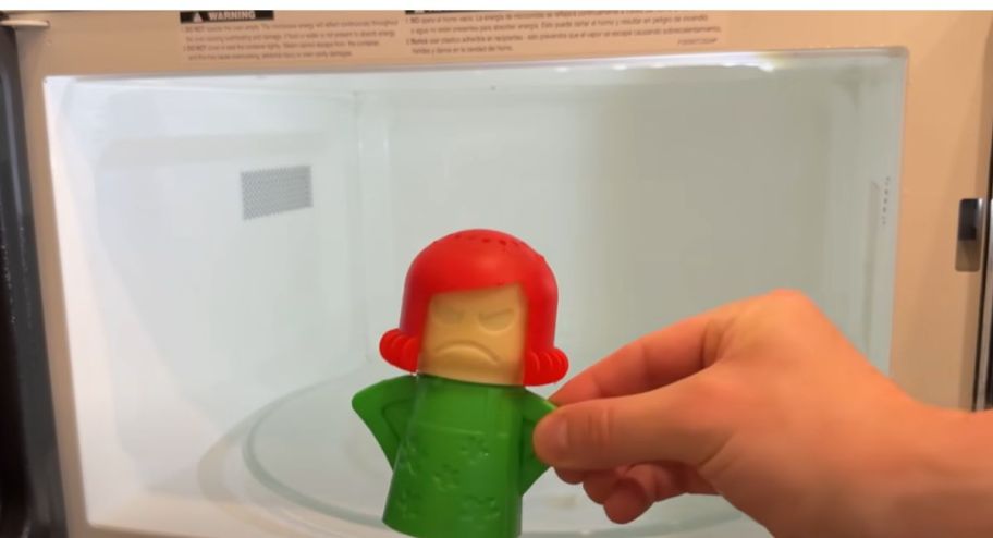 Hand holding angry mama lookalike infront of the microwave