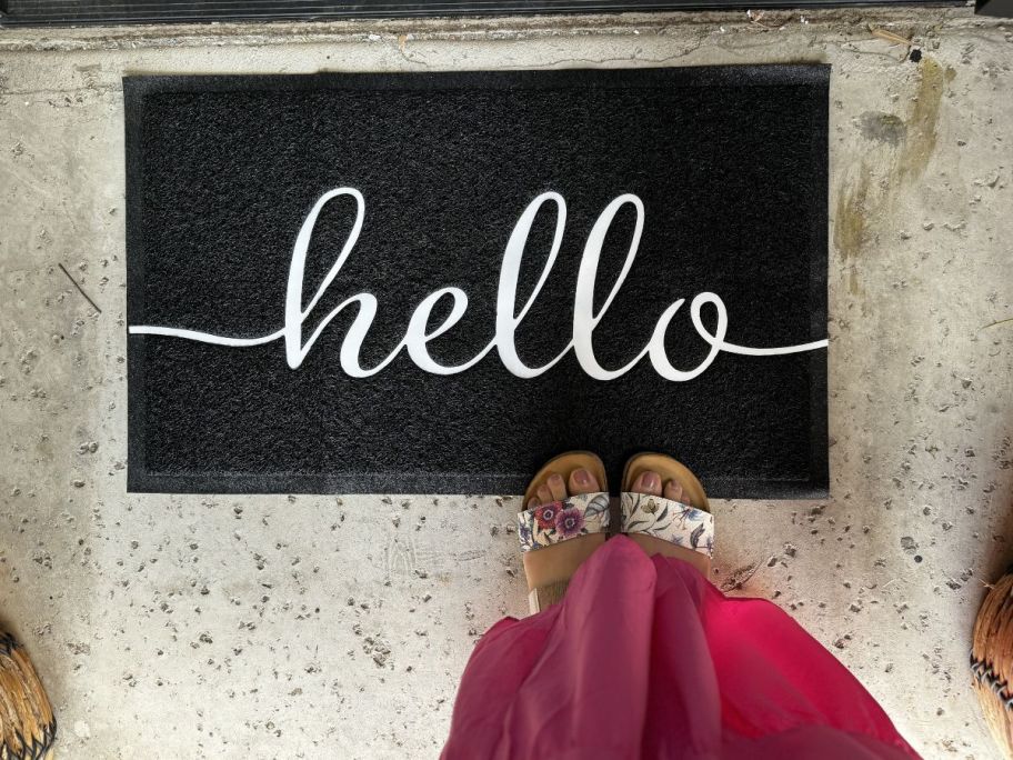 A doormat in front of a door that says "hello" 