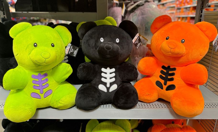 a green, black and orange gummy bear plush on a store shelf in a walmart