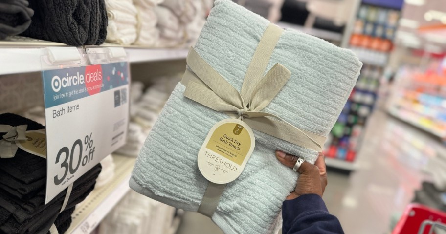 hand holding up a 2-pack of bath towels in a light blue color