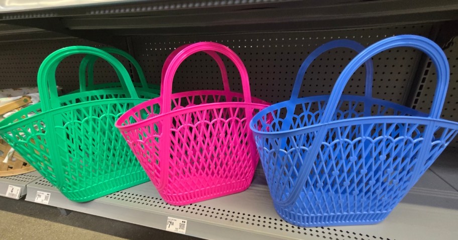 3 jelly tote baskets on a store shelf, one is bright green, one is bright pink, one is bright blue