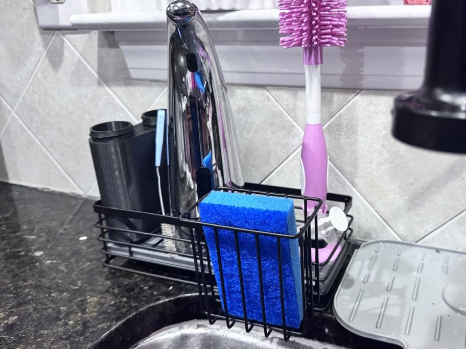 black sink caddy with sponge, soap, and brushes