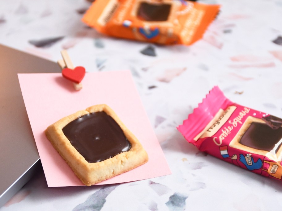 square cookie topped with chocolate on a pink piece of paper